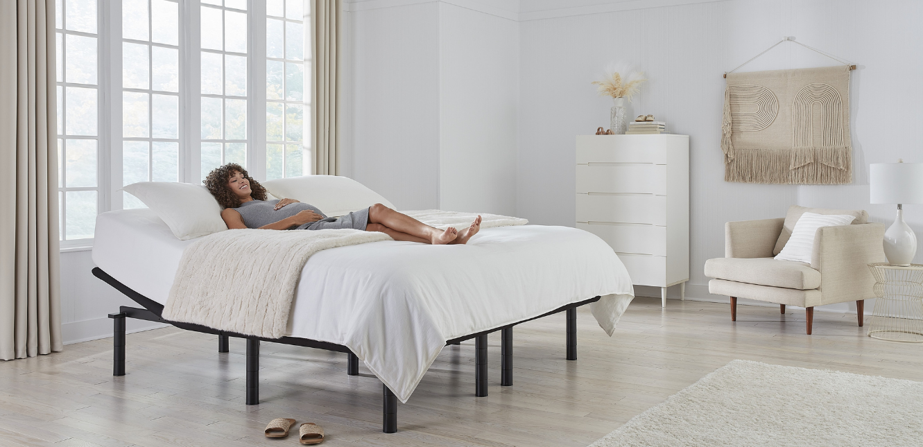 Pregnant woman lying down and holding her belly on an Ergomotion adjustable bed