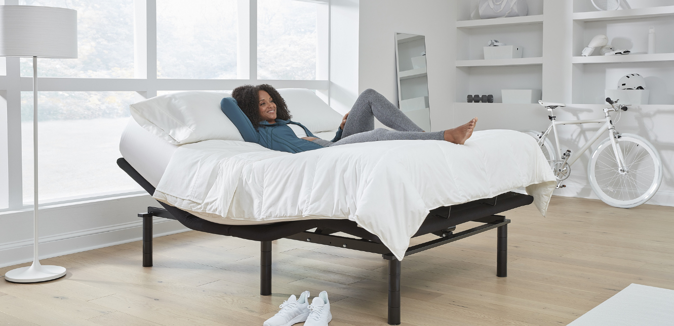 Woman lying down on a full-size adjustable bed with her feet up
